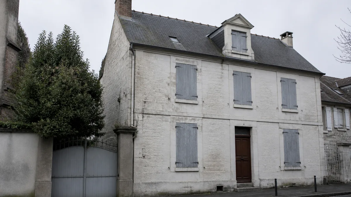 Façade d'une maison de famille ancienne aux volets fermés, dans une rue calme d'Île-de-France, aucune personne dans le cadre