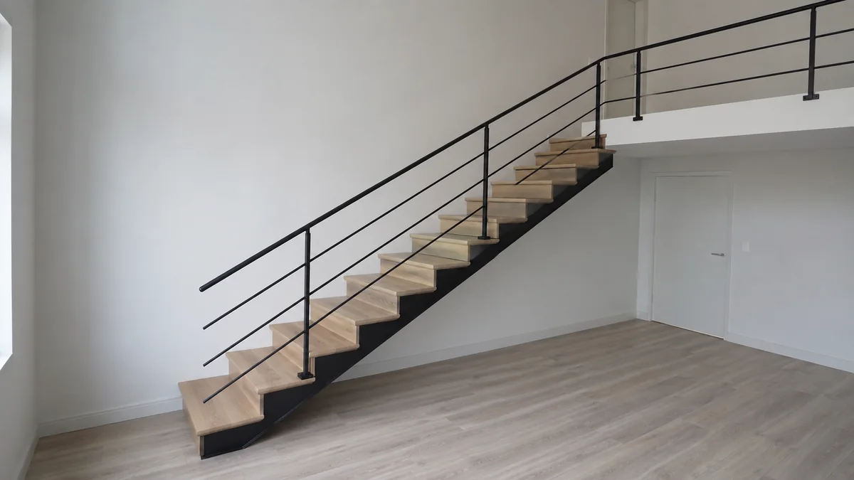 Escalier droit vu de côté, bordé d’un garde-corps métallique à lisses horizontales trop bas