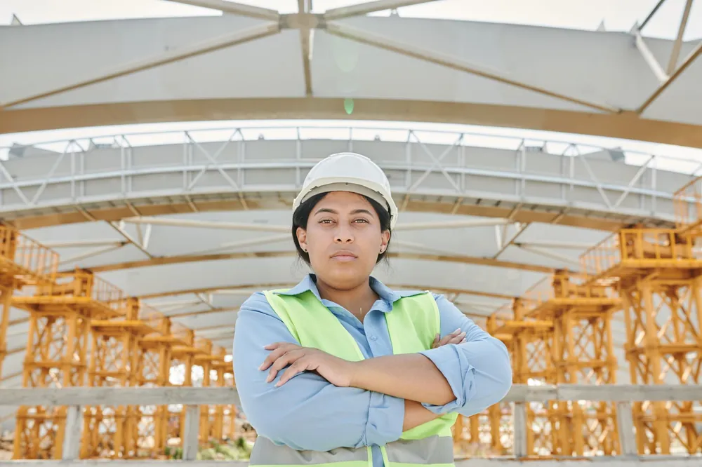 Ingénieure en équipement de sécurité sur un chantier, devant une structure métallique en cours de construction