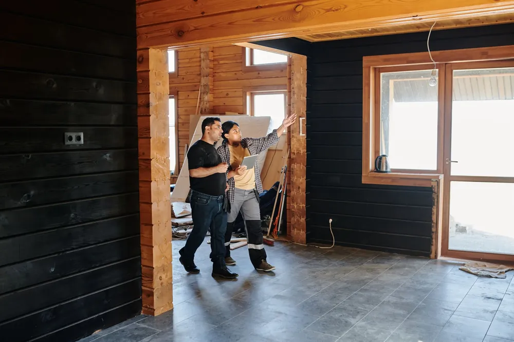 Échange entre deux personnes sur un chantier de rénovation intérieure en bois, discussion autour de travaux réalisés