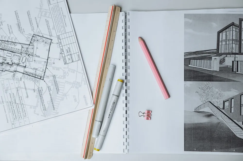 Plans d'architecte et outils de dessin technique disposés sur un bureau, préparation d'un devis d'expertise