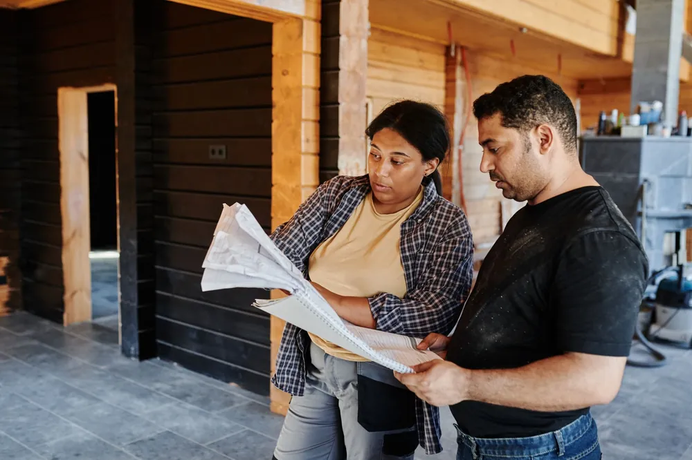 Deux ouvriers consultant des plans de construction à l'intérieur d'une structure en bois